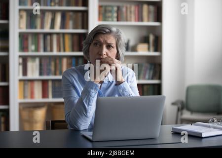 Femme d'affaires pensive et mûre inquiet utilisant un ordinateur portable Banque D'Images
