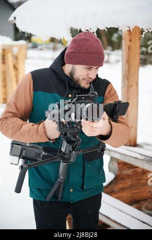 Homme vidéaste filmographie utilisant une caméra montée sur un stabilisateur de nacelle en hiver. Banque D'Images