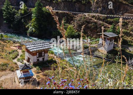 Pont au-dessus de la rivière de montagne à écoulement rapide dans l'Himalaya du Bhoutan. La rivière serpente à travers la vallée, un pont suspendu traverse le ruisseau. Le hap Banque D'Images