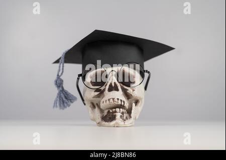 Crâne en plastique avec bonnet et lunettes universitaires. Banque D'Images