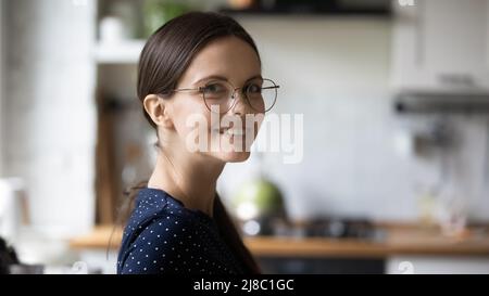 Bonne jeune femme millénaire portant des lunettes posant dans la cuisine maison Banque D'Images