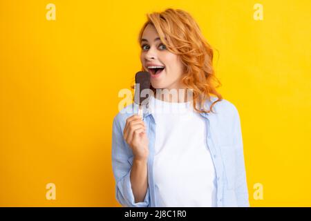 Concept d'été. Bonne femme positive tient savoureuse glace congelée, aime manger délicieux dessert froid, pose sur fond jaune, se sent heureux Banque D'Images