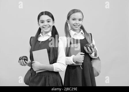 Développer les connaissances sur une alimentation saine. Les enfants tiennent des livres et des pommes. Alimentation nutritive à l'école Banque D'Images