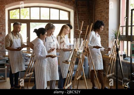 Groupe de personnes diverses peignant sur un chevalet pendant la classe d'art Banque D'Images