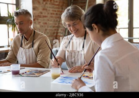 Trois élèves divers de l'école d'art peignent avec des peintures acryliques sur papier Banque D'Images