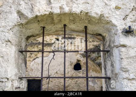 Fenêtre voûtée avec barres métalliques dans de vieilles pierres.La texture de la vieille maçonnerie en ruine.L'ancienne synagogue à moitié ruinée.Un lieu pour religieux r Banque D'Images