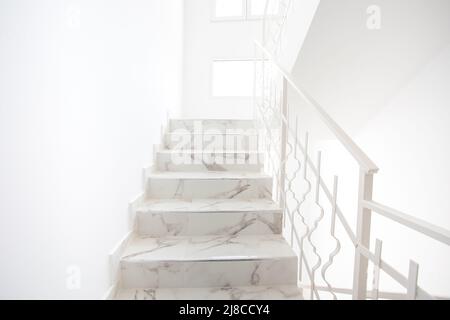 Un escalier lumineux et moderne. Les escaliers se lève où vous pouvez voir les fenêtres et la lumière. Main courante en métal blanc sur le côté. Banque D'Images