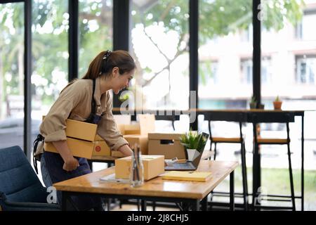 Entrepreneur PME petits entrepreneurs en ligne de vente d'idées, heureux jeune asiatique propriétaire d'entreprise travailler sur l'ordinateur et un boxs à la maison, la livraison PME Banque D'Images