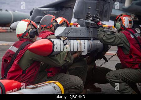 Les Marines des États-Unis chargent un missile aérien à portée moyenne avancé sur un arrieur AV-8B du corps maritime attaché au mouton noir de l'escadron d'attaque maritime 214, pendant les opérations sur le pont de vol du navire d'assaut amphibie de classe Wasp USS Essex à l'appui de l'opération Noble Fusion, le 3 février, 2022 exploitation sur le détroit de Luzon. Banque D'Images