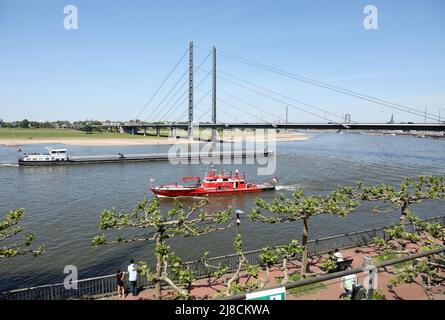 15 mai 2022, Rhénanie-du-Nord-Westphalie, Düsseldorf : un cargo et un bateau incendie naviguent sur le Rhin, devant le pont du genou du Rhin. En premier plan la promenade du Rhin . En Rhénanie-du-Nord-Westphalie, l'élection du Parlement de l'État de 18th a lieu dimanche. Photo: Friso Gentsch/dpa Banque D'Images