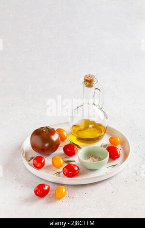 Plateau rond avec différentes variétés de tomates, sel et huile d'olive Banque D'Images