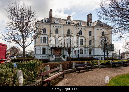 Un chemin de chippings en pierre rouge avec des bancs à intervalles réguliers passe devant le délabré mais toujours imposant Tudno en stuc blanc, Château, Hôtel, Llandudno Banque D'Images