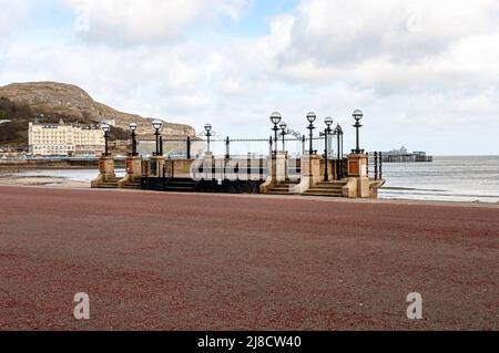 Kiosque Llandudno en béton et pierre du début du siècle 20th avec un mur arrière semi-circulaire au podium meublé de lampes en fer sur trois piliers Banque D'Images