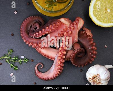 Tentacules de poulpes cuites sur une assiette d'ardoise noire servie avec des épices, de l'ail, du citron et de l'huile d'olive, vue de dessus de délicieux fruits de mer Banque D'Images