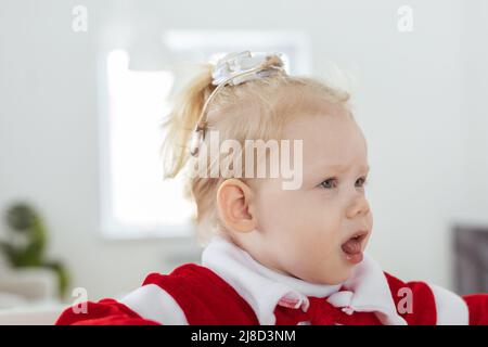 Enfant fille vêtue de la robe de noël avec implants cochléaires s'amuser à la maison - aide auditive et technologies innovantes pour le traitement de la surdité Banque D'Images