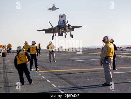 Les équipages de plate-forme de vol de la Marine américaine regardent un avion de chasse F-35B Lightning II du corps des Marines, attaché aux cols volants de l'escadron d'attaque de chasseurs marins 122, effectue un atterrissage vertical sur le pont de vol du navire d'assaut amphibie de classe Wasp USS Makin Island, le 2 février, 2022 exploitation sur l'océan Pacifique. Banque D'Images