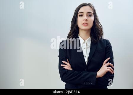 portrait d'une jeune femme d'affaires confiante entrepreneur a plié les bras portant une veste noire sur un fond blanc studio Banque D'Images