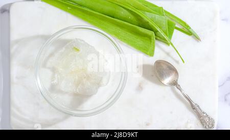 Recette maison de gommage du visage et du corps à l'aloès Vera. Gel de Vera d'aloès gros plan dans un bol en verre sur fond de marbre Banque D'Images