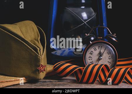Soldats russes Cap, St. George ruban, vieux livre et un réveil avec lampe au kérosène. Le jour de la victoire est le 9th mai Banque D'Images