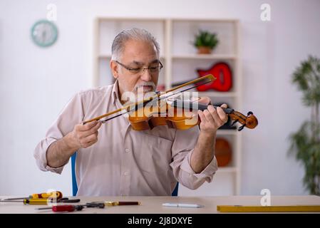 Ancien réparateur répare les instruments de musique à l'atelier Banque D'Images