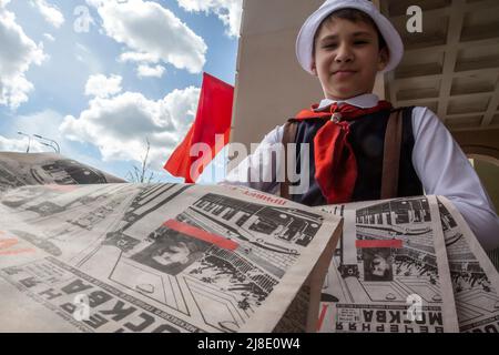 Moscou, Russie. 15th mai 2022. Un garçon habillé comme un pionnier du 1930 distribue les journaux Vechernaya Moskva 14 mai 1935 numéro avec des informations sur l'ouverture du métro à Moscou. La station Park Kultury ré-enactes, dans une rue avant une entrée à la station, la cérémonie de 1935 pour lancer la première ligne de l'histoire afin de célébrer l'anniversaire 87th du métro de Moscou, Russie Banque D'Images