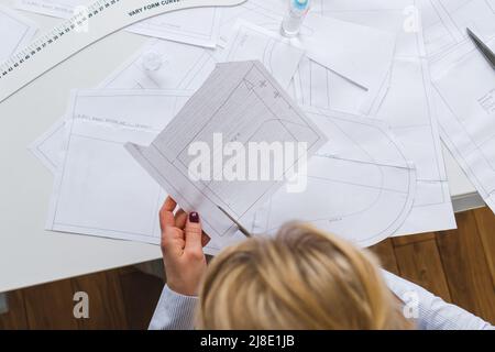 La couturière coupe des motifs de paper pour la robe avec des ciseaux. Développement de conception et création de vêtements Banque D'Images