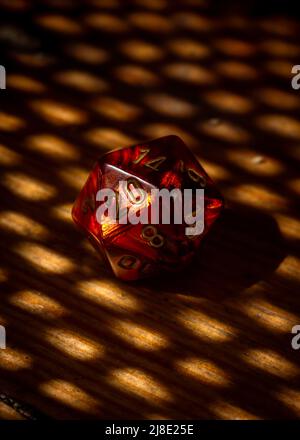 Image verticale d'une matrice de jeu de rôle rouge à 20 côtés et motif de lumière et d'ombre Banque D'Images