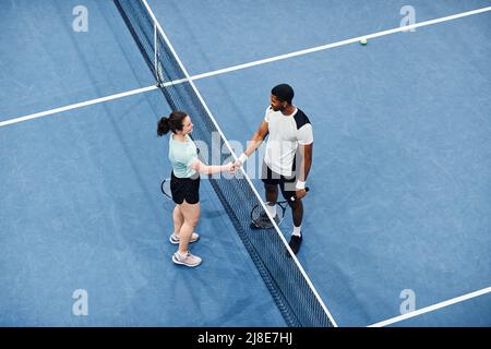 Vue minimale de dessus de deux joueurs de tennis qui se branle sur le filet pendant le match, espace de copie Banque D'Images