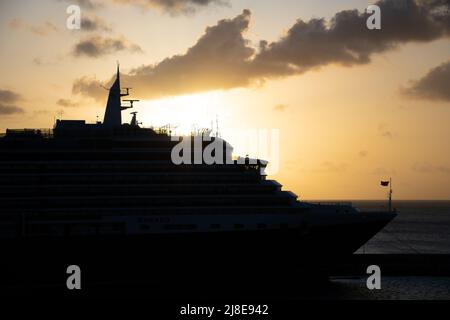 Bridgetown, Barbade - 25 mars 2022 : le soleil se couche derrière le paquebot de croisière Cunard Queen Victoria, à Bridgetown Dock Banque D'Images