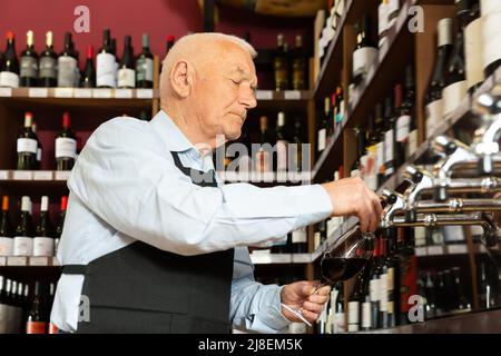 Bon vendeur versant du vin de la colonne de vin Banque D'Images