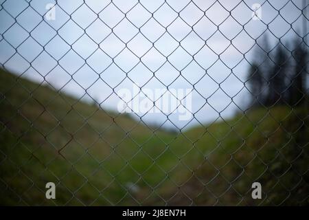 Filet de clôture. Filet d'acier sur fond de paysage. Elément répété. Texture de la clôture en fil d'acier. Banque D'Images