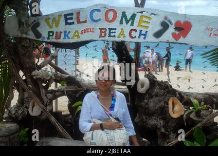 Tourisme s'asseoir sur le banc en face de bienvenue à Puka Shell Beach Sign, Boracay, les Visayas, Philippines, Asie du Sud-est. Banque D'Images