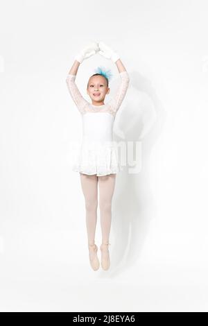 Ballerine blanche ballerine tutu jupe, noeud bleu dans les cheveux et moufles blanches dansant sur fond blanc avec ombre. Pleine longueur, prise de vue en studio Banque D'Images