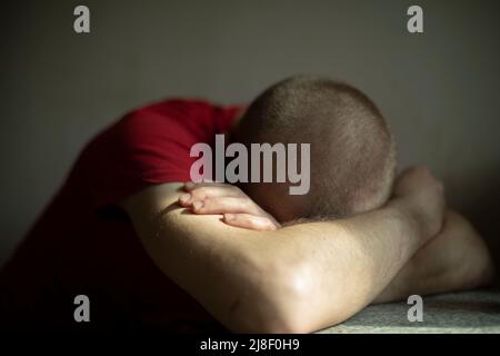 Homme fatigué. Guy dort assis. L'homme s'est endormi avec sa tête sur la table. Après une dure journée. Banque D'Images