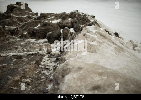 Neige sale par la route. Côté de route en hiver. Les blocs de glace sont noirs. Déneigement. Banque D'Images