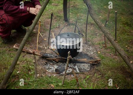 Chaudière sur le feu. Chaudière de cuisson pour le camping. Centre touristique. Un récipient pour faire bouillir l'eau sur un feu ouvert. Camp de voyageurs dans la forêt. Banque D'Images