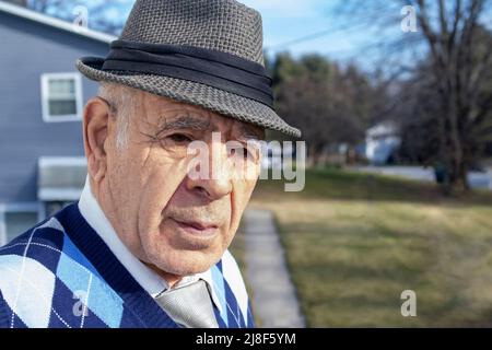 homme caucasien adulte âgé avec gilet décoratif en forme de losange bleu et cravate et chemise sur une rue de banlieue Banque D'Images