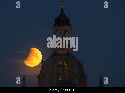 Dresde, Allemagne. 16th mai 2022. La lune se couche le matin lors d'une éclipse lunaire derrière la Frauenkirche et le dôme de la Kunstakedmie avec l'ange 'Fama'. Les spectateurs peuvent regarder une éclipse lunaire totale ce matin, mais pas partout. Dans certains endroits, la lune disparaîtra déjà derrière l'horizon dans le sud-ouest avant de plonger complètement dans l'ombre de la terre. Ainsi, les observateurs ne pouvaient en partie regarder qu'une éclipse lunaire partielle. Crédit : Robert Michael/dpa/Alay Live News Banque D'Images