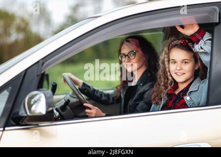 Vacances en famille et voyage. Une mère et une fille souriantes se trouvent dans une voiture de location. Le concept d'achat d'une nouvelle automobile. Banque D'Images