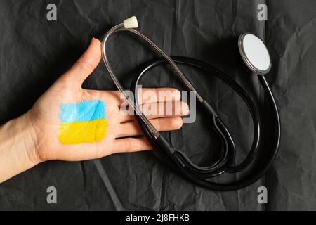 Stéthoscope en main se trouve sur le drapeau national de l'Ukraine jaune-bleu, la loi martiale en Ukraine, les soins médicaux dans la guerre Banque D'Images