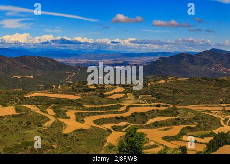 Paysage de champs en terrasse et de montagnes entourant une vallée par l'église forteresse Iglesia de Santa Maria à Ujue, Navarre, Espagne Banque D'Images