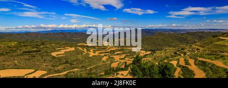 Vue panoramique sur les champs en terrasse et les montagnes entourant une vallée par l'église forteresse Iglesia de Santa Maria à Ujue, Navarre, Espagne Banque D'Images