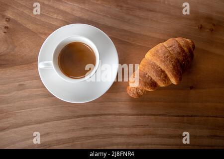 Croissant avec expresso dans une tasse blanche, vue de dessus Banque D'Images