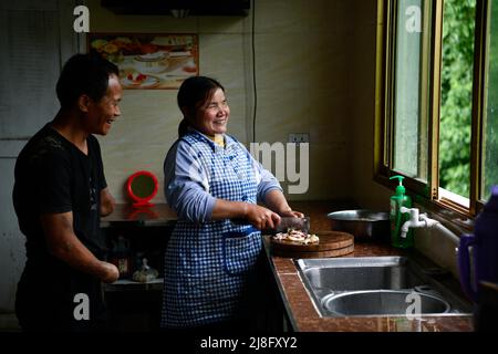 (220516) -- ZUNYI, le 16 mai 2022 (Xinhua) -- Jian Qin parle à son mari alors qu'elle se prépare à cuisiner chez elle dans le canton de Zhongguan, comté de Zheng'an, province de Guizhou, dans le sud-ouest de la Chine, le 12 mai 2022. Vivant au fond des montagnes de Zunyi, dans la province de Guizhou, Zhao Youliang et Jian Qin sont un couple handicapé. Zhao, 50 ans, a perdu les mains en raison d'une amputation à un jeune âge, et Jian, 43 ans, a perdu la vue en raison du retard dans le traitement d'une maladie dans son enfance. Dans la vie quotidienne, Zhao aide sa femme à voir avec ses yeux, tandis que Jian aide son mari avec sa main Banque D'Images