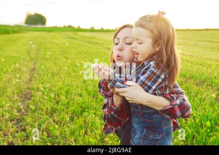 mère avec sa fille dans le champ soufflant un dendelion Banque D'Images