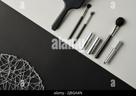 Flatlay de rangée d'accessoires de maquillage et de soins de beauté tels que des pinceaux de poudre et d'ombre et des rouges à lèvres dans des étuis en argent sur la surface gris clair Banque D'Images