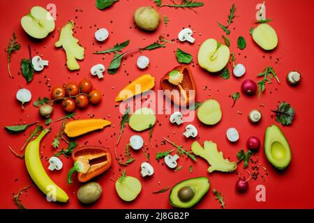 Vue de dessus des fruits biologiques coupés, des légumes et des épices sur fond rouge Banque D'Images