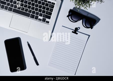Composition d'un clavier d'ordinateur portable, papier vierge avec clip, lunettes de soleil, stylo, et smartphone sur le lieu de travail de la personne d'affaires moderne Banque D'Images