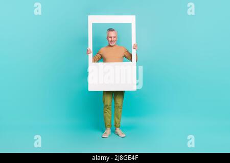 Photo de corps complet de drôle homme gai tenir papier fenêtre usure chandail isolé sur fond de couleur sarcelle Banque D'Images