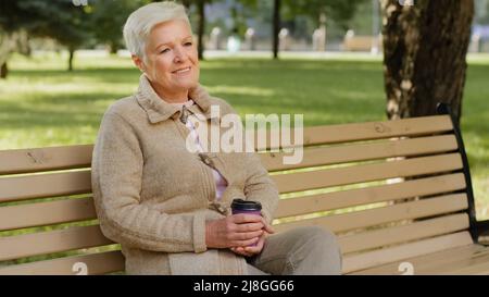 Visage ridé de 60s heureuse femme âgée à l'extérieur dans le parc regardant de côté ayant le grand sourire, implants dentaires et prothèses satisfait portrait de client Banque D'Images